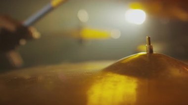 Sahnede altın sarısına odaklanmış davul sesi çıkartırken çubuk kullanan tanınmayan caz müzisyeninin yakın çekimi.