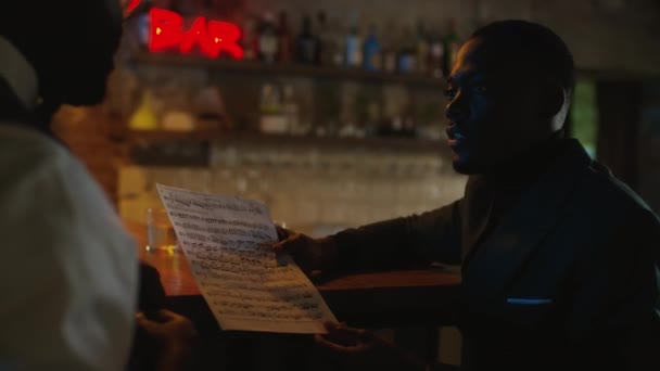 바에서 카운터에 앉아있는 음악을 아프리카계 남자의 — 비디오