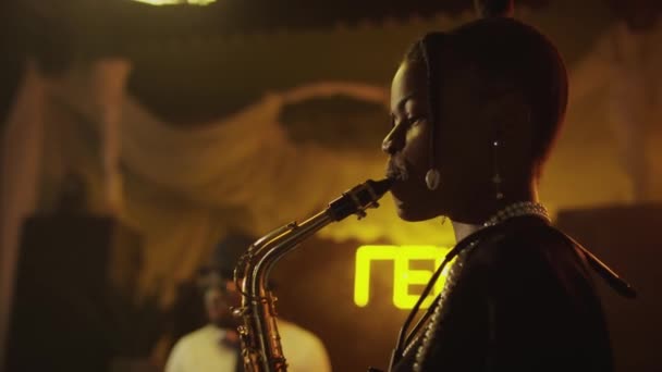 ファンシーなヴィンテージジャズクラブでステージでジャズミュージックを演奏する若いアフリカ系アメリカ人女性サクソフォニストのショットをトリミング — ストック動画