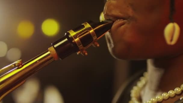 非洲裔美籍女声萨克斯演奏家在带着暖黄灯光的爵士俱乐部舞台上演奏音乐的服装 — 图库视频影像