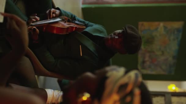 アフリカ系アメリカ人のジャズ ミュージシャンがヴァイオリンを演奏しながら レトロスタイルのスタジオでバンドと共に新しい曲に取り組む垂直オーバーショルダー — ストック動画