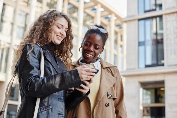 Waist Portrait Two Smiling Young Women Using Smartphone While Standing — Stock Photo, Image