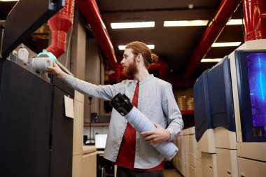 Endüstriyel baskı makinesinin mürekkep depolarını dolduran genç adamın yan görünüm portresi