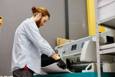 Endüstriyel matbaada toplu baskı kalitesini kontrol eden genç adamın yan görünüm portresi, kopyalama alanı