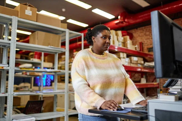 Waist up portrait of adult black woman using computer while setting up printing machines in industrial shop,copy space