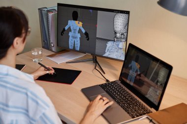 Genç bayan tasarımcı iş yerinde video oyunu karakterleri için dijital 3D modeller yapıyor ve kalem tableti kullanıyor