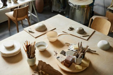 Samimi çömlekçilik stüdyosundaki masada kil ve sanat malzemelerinin yüksek açılı arkaplan resmi, boşluğu kopyala