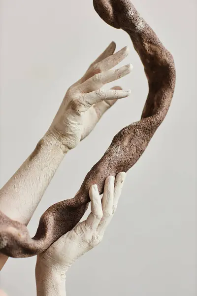 Close up of elegant hands covered in paint holding ceramic art piece minimal