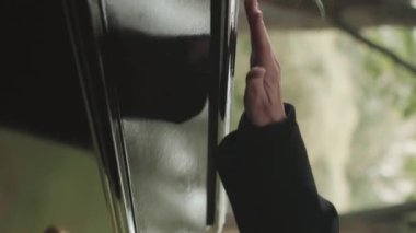 Dışarıdaki cenazede tabutun siyah ahşap kapağına yerleştirilmiş tanınmayan kadın elinin dikey kesikli görüntüsü.