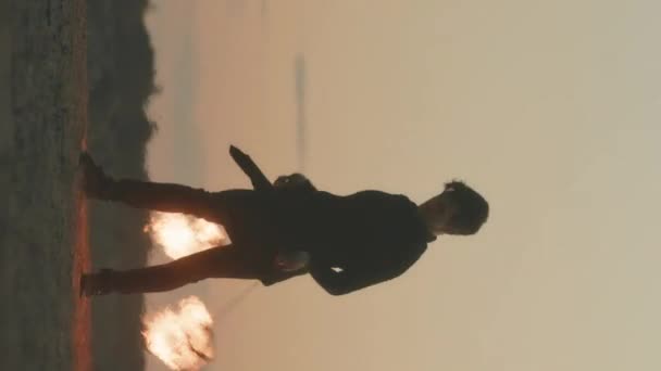 夏のフェスティバル中にサンディビーチでサンディービーチで火のショーを示しながら 勇敢な若者の完全な縦のショット — ストック動画