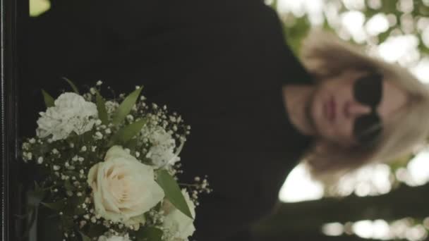 Вертикальный Снимок Белой Женщины Черной Одежде Солнцезащитных Очках Смотрящей Гроб — стоковое видео