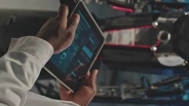 Karanlık laboratuarda dijital tablet kullanılarak insan robotunu kontrol eden tanımlanamayan elektronik mühendisinin dikey kırpılmış görüntüsü