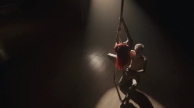 Yüksek açılı, beyaz tenli birkaç dansçının, karanlık stüdyoda, paruqt zeminli projektör ışığı altında baştan çıkarıcı bir şekilde dans edişinin fotoğrafı.