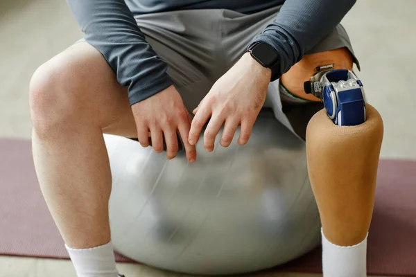 在家锻炼时 坐在健身球上的假腿男子近身 — 图库照片