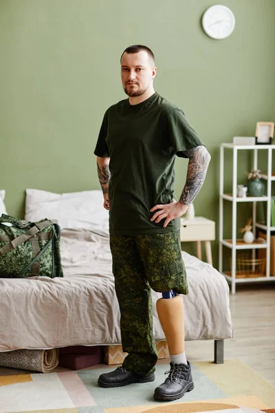 Full length portrait of military veteran with prosthetic leg wearing army uniform and looking at camera