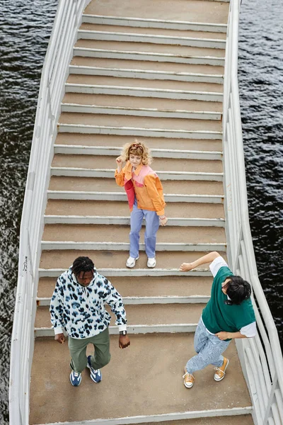 Graphic top view of group of young people dancing on stairs outdoors and wearing colorful street style clothes