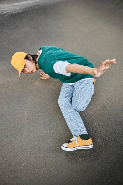 Top view of young Asian man dancing hip hop outdoors and wearing colorful street style clothes