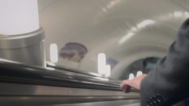 Metroda yürüyen merdivenden inerken elini korkuluklara koyan tanınmamış iş adamının eli.