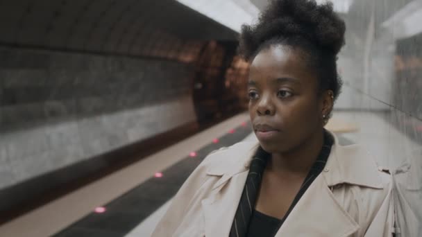 一个孤独的年轻黑人女人看着地铁列车到达车站时的慢吞吞的喘息 — 图库视频影像