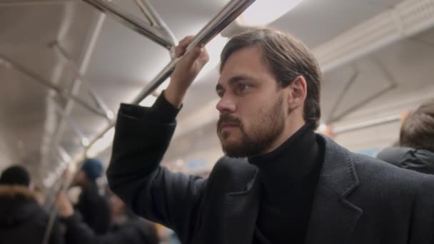 黒いタートルネックで白人若いビジネスマンのスローモをチェストし 地下鉄の列車に乗りながら周りを見回し 手でレールを保持 — ストック動画