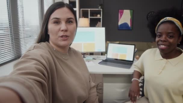 两名年轻的多族裔女同事在现代办公室共同录制视频时手持Pov — 图库视频影像