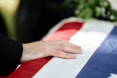 Erkek eli tabutun üzerinde, Amerikan bayrağı da açık hava cenaze töreninde asker için fotokopi çekilecek.