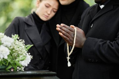 Açık hava cenaze töreninde siyah giyip dua eden ve tespih tutan insanları kapatın.