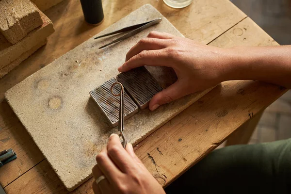 手工操作的珠宝商用镊子在粗糙的木桌上握着手工制作的戒指的俯瞰特写 — 图库照片