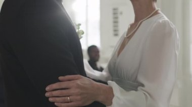 Beyaz şapelde güzel bir düğün töreninde öpüşen yeni evli, beyaz, olgun bir çifti yavaşça yukarı kaldır.