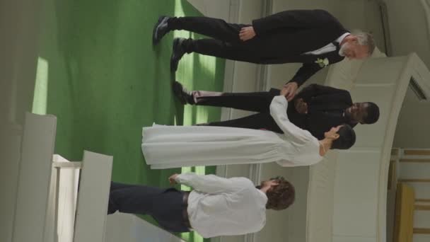 在教堂举行的舒适的婚礼上 白人成人夫妇交换结婚戒指 黑人男性官员宣布他们的丈夫 妻子和摄影师合影的垂直全景照片 — 图库视频影像