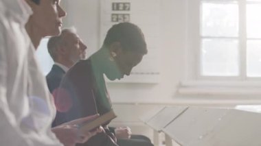 Kilisede ayin sırasında kilisede birlikte otururken papazın vaaz vermesini dinleyen siyahi kadın ve diğer çeşitli cemaat mensuplarının belindeki lensler alevlendi.