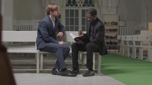 非洲裔美国男牧师在白人教堂的长椅上与白人教区牧师私下交谈 这是一个很长的镜头 — 图库视频影像