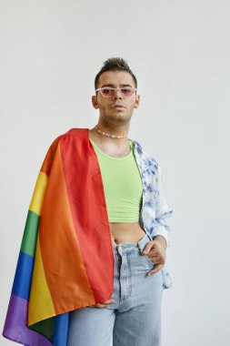 Beyaz arka planda gururla sarılı genç bir gay 'in dikey portresi