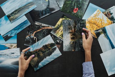 Kadın fotoğrafçının elleri bastığı pelerinlerin fotoğraflarını kontrol ediyor.