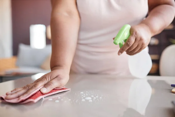 Close up of unrecognizable black woman cleaning kitchen counter and using spray bottle, copy space
