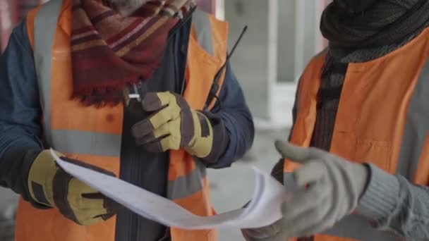 Tilting Shot Two Multiethnic Workmen Hardhats Safety Vests Standing Construction — Vídeos de Stock