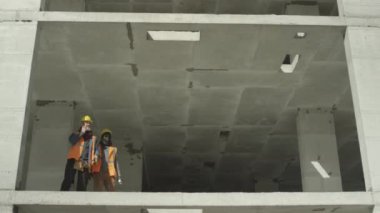 İki profesyonel mühendisin güvenlik yelekleri ve kasketleri ile bitmemiş çok katlı bir binanın beton bloğunun kenarında dikilip tartışırken çekilmesi zor bir ihtimal.