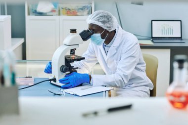 Tıbbi laboratuvarda mikroskop kullanan siyah bilim adamının yan görüş portresi, boşluğu kopyala