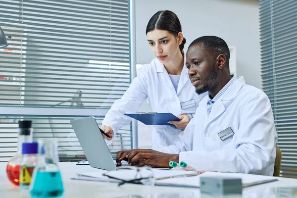 Portrait of two scientists using laptop while doing research in medical laboratory, copy space