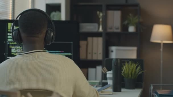 若い白人女性オフィスワーカーのミディアムショットは スクリーン上のプログラムコードを持つデスクトップコンピュータの前に座っている黒人男性プログラム開発者と話す手でコーヒーのカップで — ストック動画