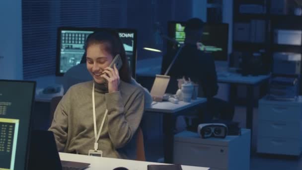 若い白人女性プログラマーが夜のサイバーセキュリティオフィスで同僚と一緒にスマートフォンで話すのを待つ — ストック動画
