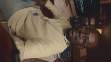 Genç Afrika kökenli Amerikalı erkek ağ mühendisinin dikey POV 'u gece karanlık ofiste program kodlarken videosunu kaydediyor.