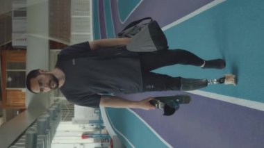 Kafkas sakallı genç sporcunun dikey çekimi. Kapalı alan eğitimi için stadyuma geliyor. Spor çantasıyla pistte güvenle yürüyor ve neşter taşıyor.