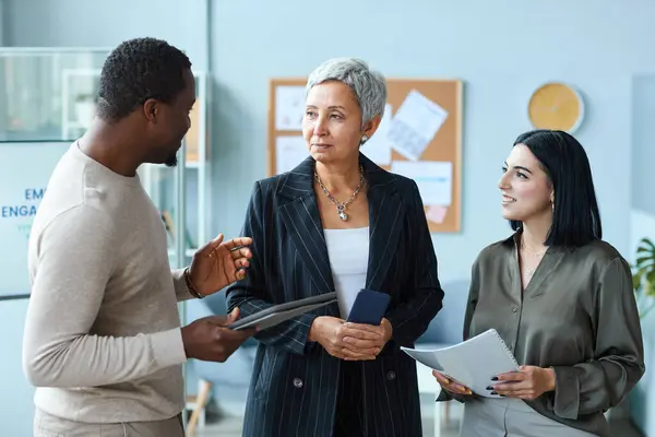 stock image Waist up portrait of senior businesswoman talking to employees while standing in office