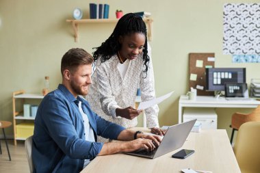 Dizüstü bilgisayar kullanan iki genç meslektaşın yan görünüm portresi tasarım bürosunda çalışırken, boşluğu kopyala