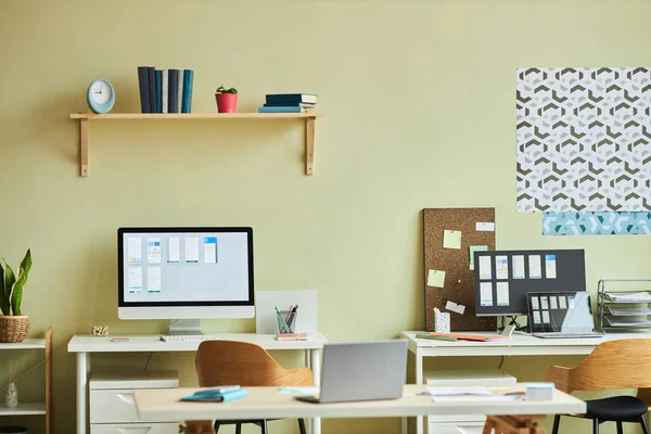 Background image of minimal office interior with computers on desks and pastel yellow wall, copy space