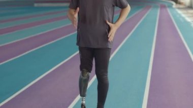 Beyaz tenli genç erkek sporcunun kapalı pistte egzersiz yaparken, yüksek dizleriyle yarışa hazırlanırken görüntüsü.