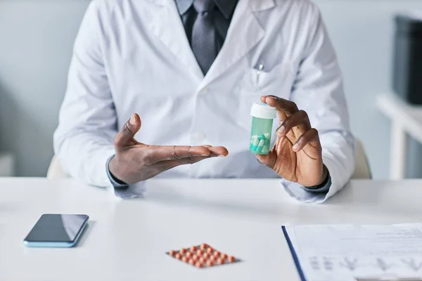 黑人医生拿着药瓶在解释药物副作用时的极小特写 — 图库照片