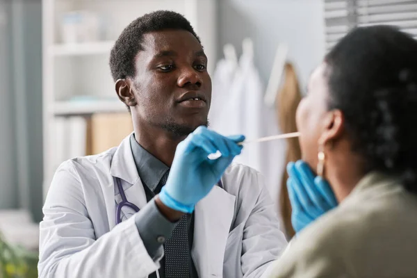 Close up portrait of young black doctor examining patients in clinic