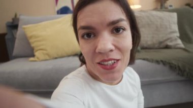 Cüceliği olan genç beyaz bir kadının, gündüz evde otururken kameraya konuştuğu video blogunu kaydeden ele avuca sığmaz görüntüsü.